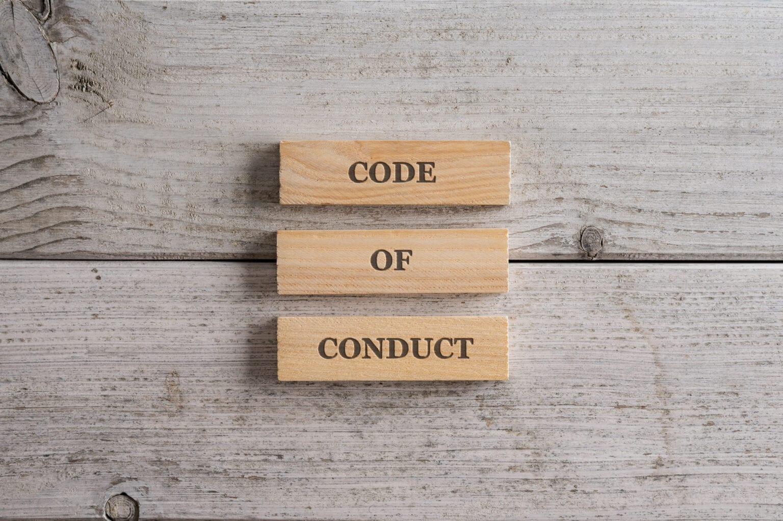 Das Schild mit dem Code of Conduct steht auf einem Stapel von drei Holzblöcken