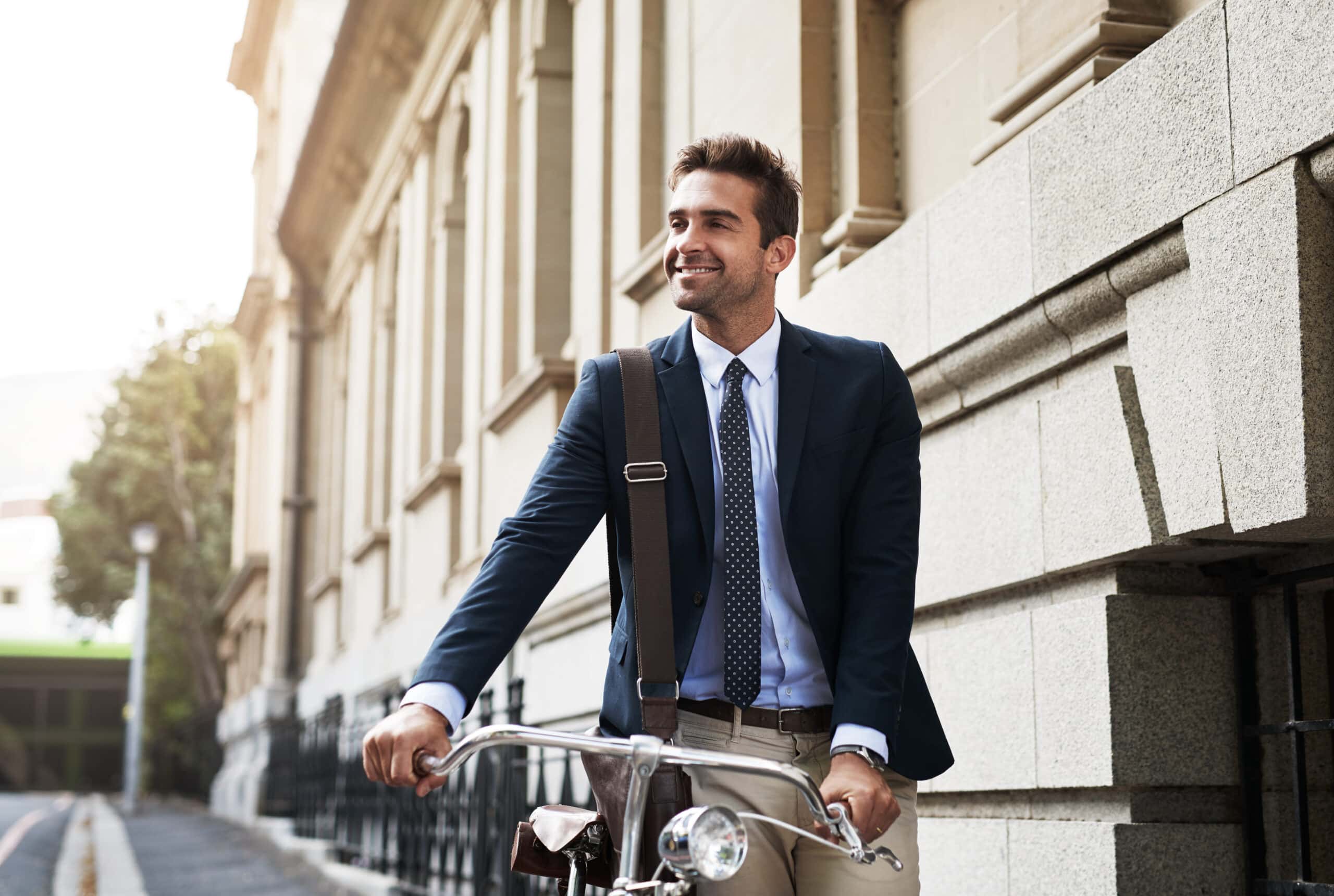 Mann freut sich mit seinem bikleasing Fahrrad an einem schönen Tag zur Arbeit zu fahren