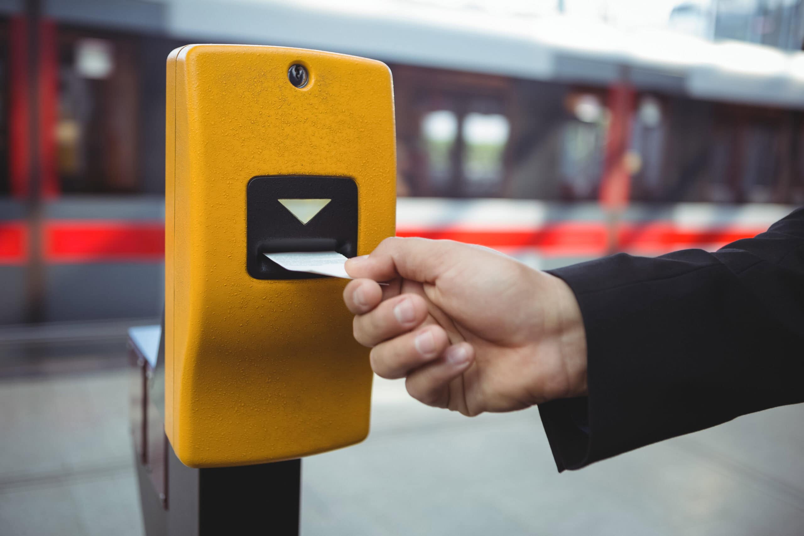 Hand eines Geschäftsmannes, der auf dem Bahnsteig ein Ticket locht