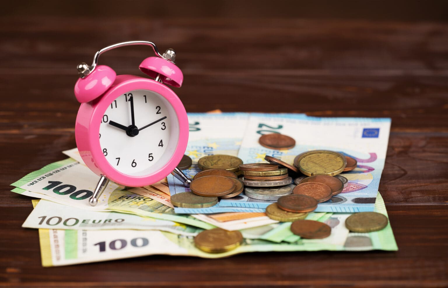 Lohnnebenkosten, dargestellt durch einen Wecker mit Euro-Geldscheinen und Münzen.