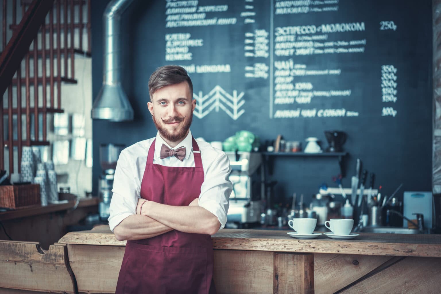 Junger Barkeeper in einer Schürze mit Minijob und Sachbezug.