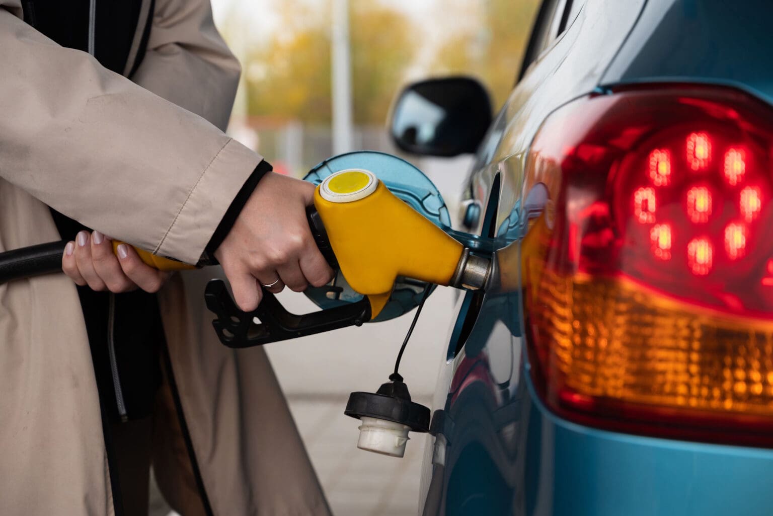 Eine Frau nutzt ihren Tankgutschein und betankt an einer Tankstelle ein Auto mit Benzin.